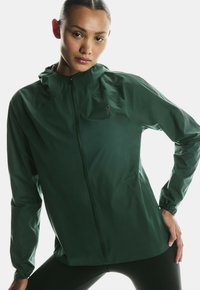 Roheline kerge jakk, millel on tõmbluku sulgemine, kapuuts ja pikad varrukad. Valmistatud siledast, tõenäoliselt veekindlast materjalist, millel on minimaalne bränding.