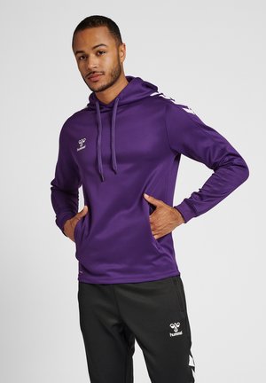 Lila Hoodie mit langen Ärmeln und Kordelzügen, ausgestattet mit einer Vordertasche und einem weißen Logo. Kombiniert mit schwarzen Hosen und weißen Logodetails.