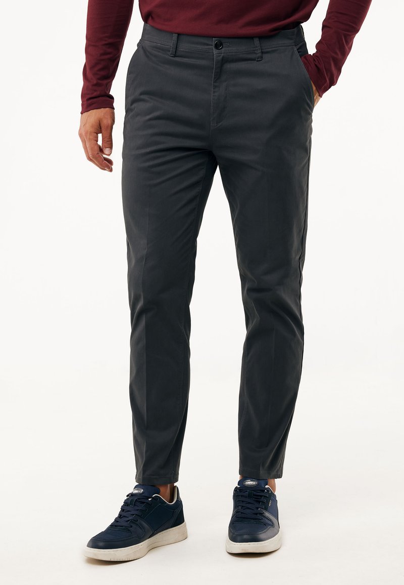 Ciemnoszare chinosy o slim fit, wykonane z trwałego materiału. Posiadają zapięcie na guzik oraz boczne kieszenie, w zestawie z granatowymi trampkami.