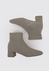 Bottes chevilles grises en matériau texturé avec un talon épais. Le design présente une forme épurée et ajustée avec une couture minimaliste.