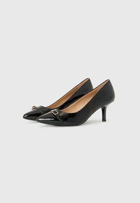 Tacones altos de charol negro con punta afilada, que cuentan con una correa decorativa y un detalle de hebilla dorada. Tacón de aguja, diseño elegante.