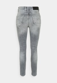 Jeans ajustados de denim gris claro, con cintura alta, dos bolsillos traseros y un leve efecto de desgaste. La cinturilla tiene un acento negro.