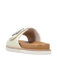 Slide sandal with a textured ivory upper, a tan footbed, and a white rubber sole; features a decorative metallic accent on the strap.