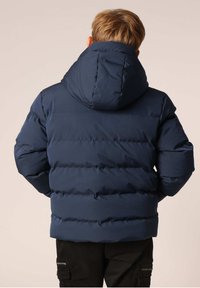 Marineblauwe pufferjack met capuchon, met een geborduurd ontwerp en textuurstof. Zichtbare stiksels en elastische manchetten.