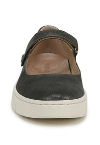 Chaussure en daim noir avec un bout arrondi, semelle en caoutchouc blanche et une sangle à boucle sur le cou-de-pied. Doublure intérieure douce visible.