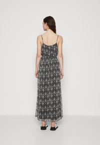 Rochie maxi alb-negru cu un model floral, talie elastică, bretele ajustabile și un design fluid care ajunge până la jumătatea gambei.