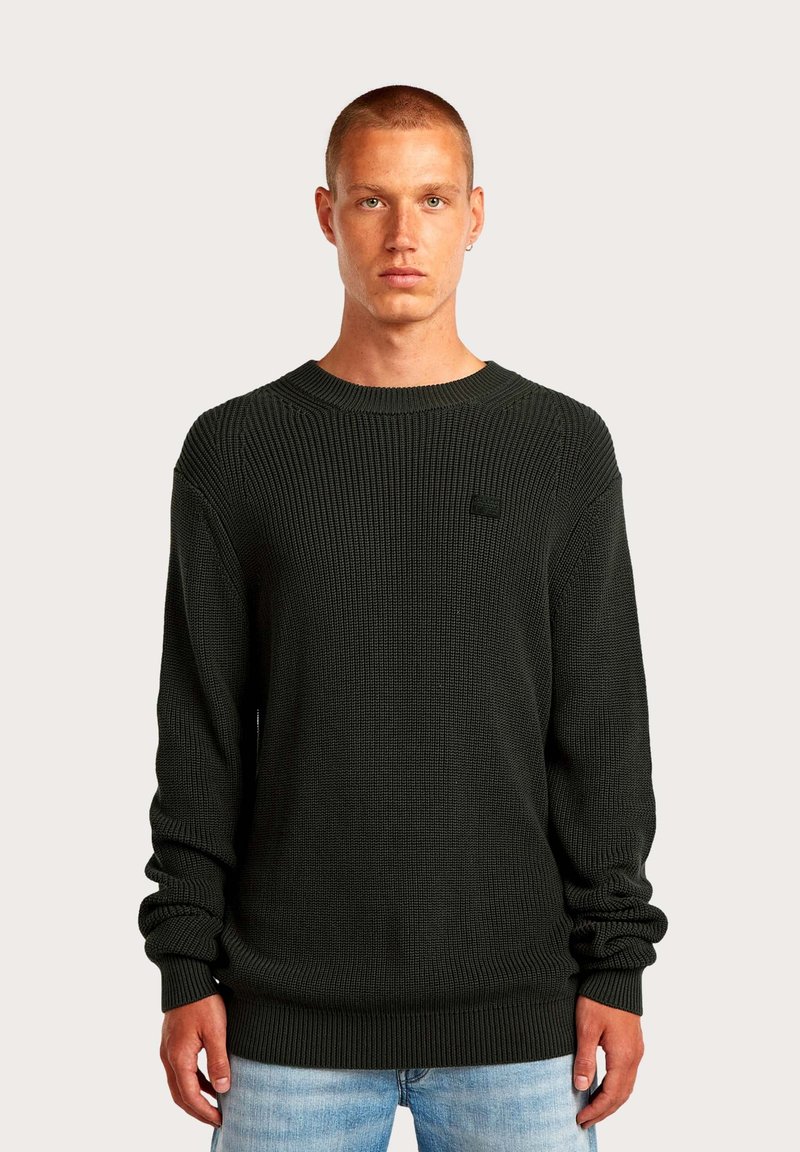 Maglione verde scuro a coste con maniche lunghe, scollo rotondo e motivo strutturato. Presenta un piccolo logo sul petto e un orlo aderente.