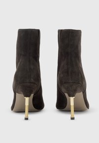 Stivaletti neri in suede con punte affusolate, fili di stiletto dorati sottili e una texture liscia; design minimalista con una silhouette elegante.