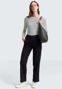 Gestreepte lange mouwen top in wit en zwart, gecombineerd met zwart op maat gemaakte broeken; houdend een donkergrijze tote bag en draag wit sneakers.