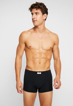 Schwarze Baumwoll-Boxershorts mit enganliegendem Design, ausgestattet mit einem elastischen Bund und einem Etikett auf der Rückseite. Glatte Textur, minimale Details.