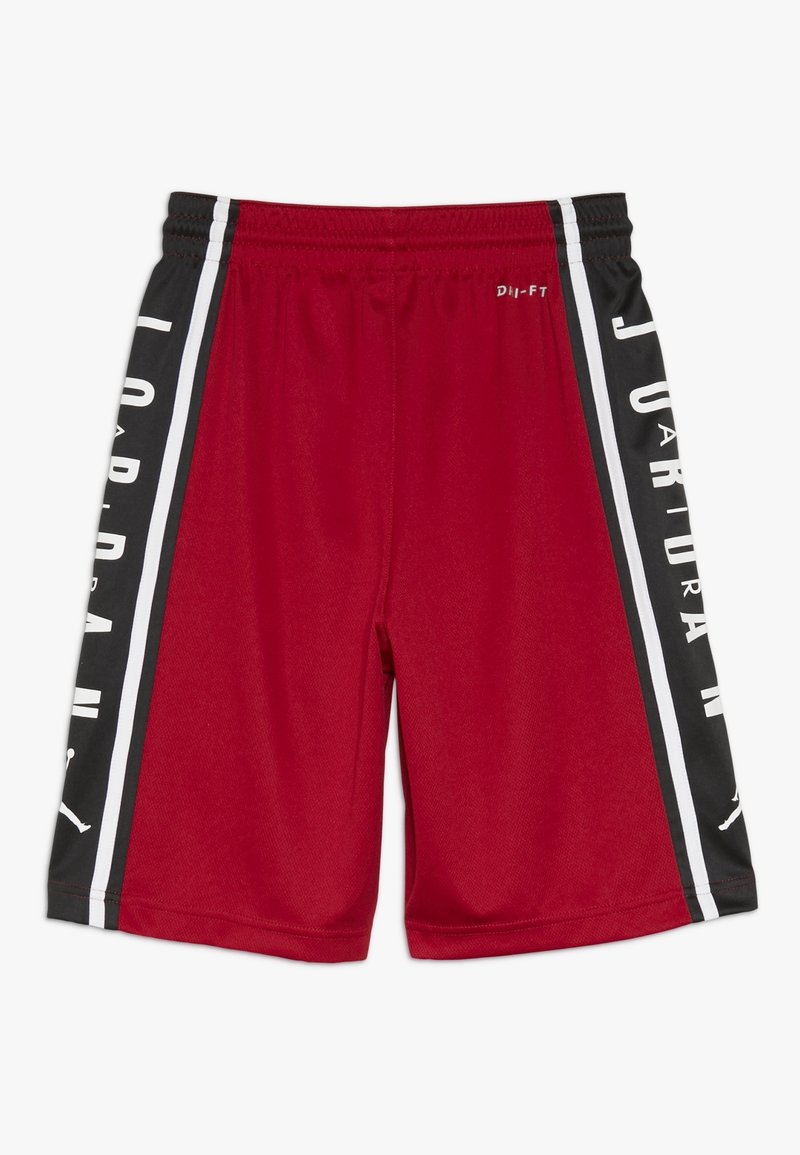 Shorts de sport rouges avec des panneaux latéraux noirs, texte vertical blanc "JORDAN" et une ceinture élastique. Petit logo blanc "Dri-FIT" près du haut.