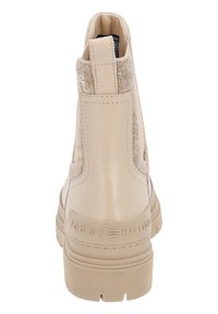 Botín beige hasta el tobillo con parte superior de cuero y paneles laterales de fieltro, con una suela de goma gruesa y un logo grabado en el talón.