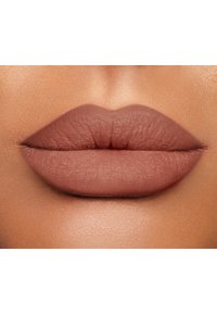 Rossetto opaco e nude applicato su labbra piene; texture liscia con un finish naturale. Le labbra sono ben definite e uniformemente colorate.