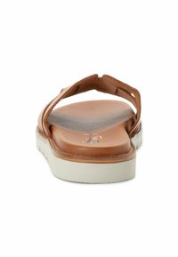Brun lædersandal med en bagrem og tekstureret indersål. Hvid gummisål med en let kurve, der har minimal dekoration og en glat finish.