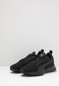 Scarpe sportive nere con tomaia in rete, pannelli texturizzati, punta arrotondata e accenti rossi del logo sulla linguetta e sul lato. Design leggero.