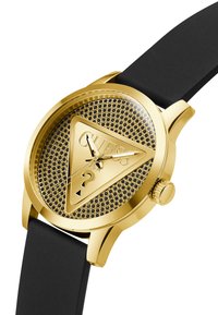 Montre dorée avec un cadran triangulaire texturé, lunette noire et bracelet en caoutchouc. Présente un design en maille et un logo de marque bien en évidence.