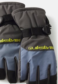 Šedé a modré zimní rukavice s polstrovaným designem. Obsahují nastavitelné černé poutko a logo „Quiksilver“ v jasně žluté barvě. Vhodné do chladného počasí.