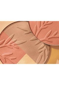 Palette de maquillage compacte comprenant deux poudres circulaires : une pêche avec un embossage en forme de feuille, une brune chaude avec une texture lisse, toutes deux dans des tons atténués.