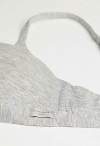 Grijze, zachte katoenen beha met een naadloos ontwerp, verstelbare bandjes en een label met de tekst "Intimissimi Natural" aan de onderkant.