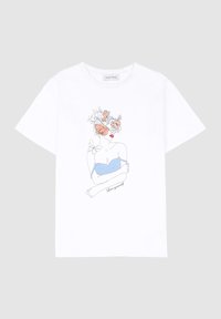 Bílý bavlněný tričko s grafikou postavy s květinovými akcenty, která má na sobě modrý top, a textem "Miluj sám sebe" pod tím.