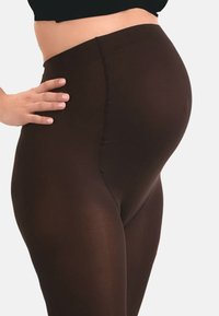 Brune leggings lavet af strækbart materiale, med en glat tekstur og et høj talje-design. Tætsiddende og lette.
