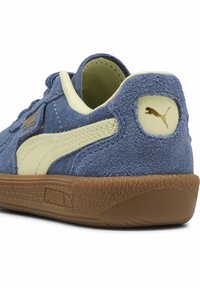 Blå mockaskor med gula detaljer, texturerad sula och logotypdetaljer. Har en vadderad krage och kontrasterande sömmar.