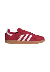 Baskets rouges Adidas Samba avec des bandes blanches, une semelle en gomme et le texte doré « SAMBA » sur le côté.