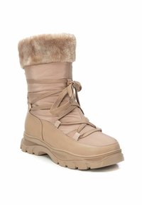 Bota impermeable beige con puño de piel sintética, diseño de cordones, suela de goma y parte superior sintética texturizada para mayor agarre y comodidad.