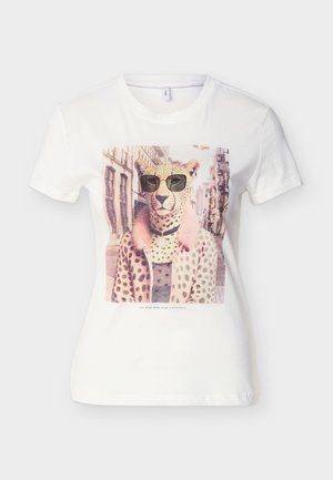 Άσπρη μπλούζα με τυπώμα ενός τσιτάχ που φορά γυαλιά ηλίου και ένα ρόζ παλτό με βούλες, με φόντο έναν αστικό δρόμο.