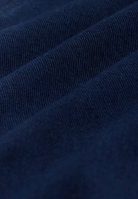 Gros plan sur un tissu bleu marine avec une texture tricotée douce et un motif de tissage diagonal visible.
