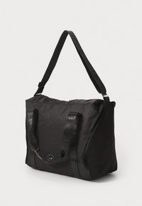 Black nylon tote bag with adjustable straps, zip closure, and subtle branding on the front. Smooth texture and rectangular shape.