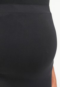 Černá sukně z elastické látky, s hladkým povrchem, přiléhavým střihem a širokým pasem pro pohodlí.