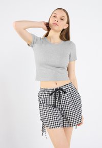 Gray, fitted short-sleeve t-shirt made of ribbed fabric; paired with black and white gingham check shorts featuring an elastic waistband and side ties.