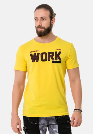 Gelbes Baumwoll-T-Shirt mit einem auffälligen schwarzen "WORK"-Graphic, Rundhalsausschnitt und kurzen Ärmeln. Sanfte Textur mit einer figurbetonten Passform.