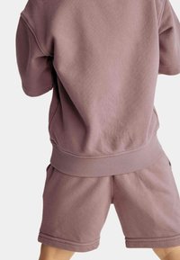 Conjunto de algodón combinado en color púrpura claro que incluye un sudadera de corte relajado y pantalones cortos a juego con puños y cintura acanalados.