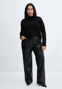 Maglione nero a maglia con collo alto, abbinato a pantaloni larghi in finta pelle nera. Tessuto liscio e vestibilità sartoriale.