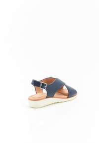 Sandalo blu navy con tomaia strutturata, design open-toe, cinturino alla caviglia regolabile e suola imbottita di colore chiaro con base decorata.
