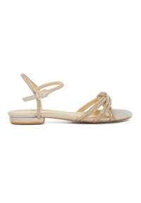 Flat sandals with a glittering gold material, featuring multiple intertwining straps and a delicate ankle strap with a buckle closure.