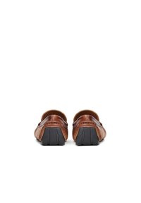 Zapatos de piel marrón tipo slip-on con forma redondeada, que presentan una superficie texturizada y suelas de goma negra. Detalles de costura a lo largo de los bordes.