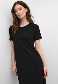 Black T-shirt dress in soft, smooth fabric. Features short rolled sleeves, a round neckline, and a relaxed, loose-fitting silhouette.