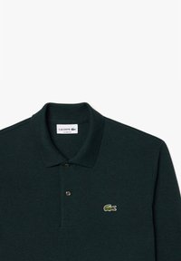 Dunkelgrünes Poloshirt aus strukturiertem Stoff, mit einer Drei-Knopf-Leiste und gesticktem Krokodil-Logo auf der linken Brust. Klassische Passform.