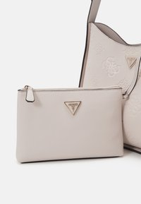 Borsa a mano in pelle grigia chiara con hardware dorato, caratterizzata da un motivo con logo in rilievo. Include una pochette coordinata staccabile con chiusura a zip.