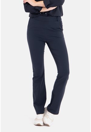 Marineblauwe, elastische broeken met een strakke pasvorm, platte tailleband en zijzakken, gecombineerd met witte sneakers voor een casual look.