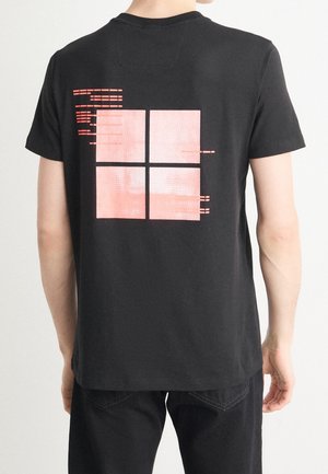 Czarny bawełniany T-shirt z teksturowanym różowym grafiką czterech kwadratów na plecach, z poziomymi liniami i subtelnym efektem gradientu.