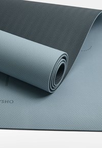 Joga mat v svetlo modri in temno sivi barvi, z teksturirano površino z diamantom in gladkim valovitim vzorcem na hrbtni strani.