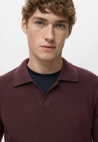 Bordowy prążkowany sweter polo z dekoltem w kształcie litery V i podwiniętym kołnierzem, noszony na granatowej koszuli. Gładka faktura, dopasowany krój.