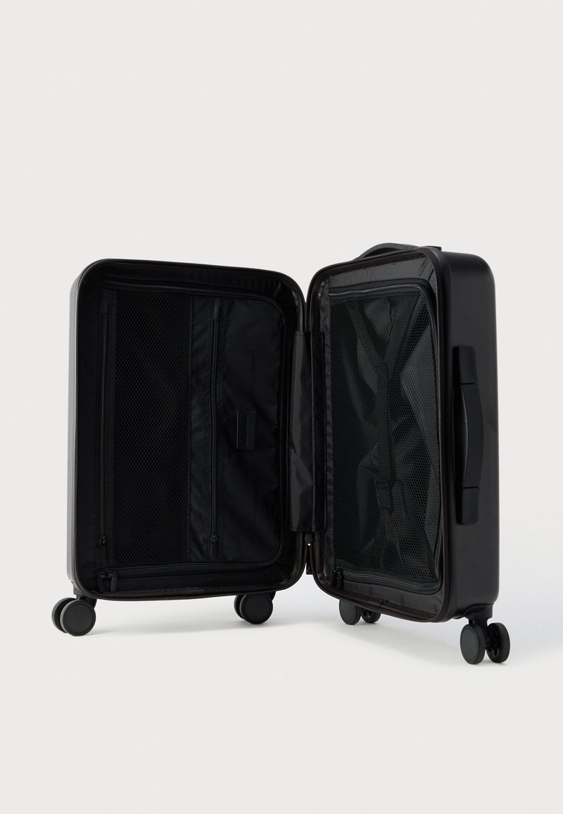 Hard-shell black suitcase with two compartments, mesh pockets, and a zipper closure. Features four wheels for easy mobility.