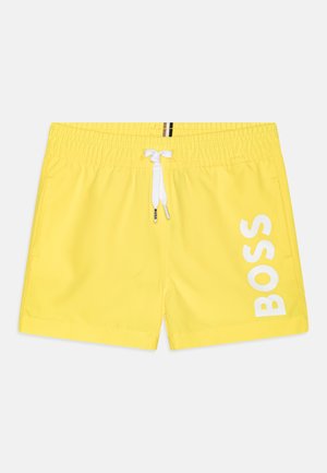 Costumi da bagno gialli con vita elastica, laccetto bianco e grande logo "BOSS" bianco sul lato. Tessuto leggero e liscio.