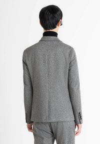 Chaqueta de traje gris texturizada con solapas de muesca y puños de tres botones, que presenta un corte ajustado y un diseño minimalista.