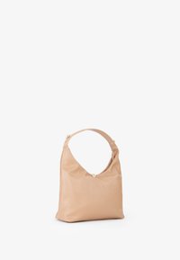 Beige leren handtas met een gebogen silhouet, een enkele schouderband en een ronde sluiting aan de bovenkant. Bevat minimale hardware accenten.